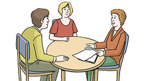 Drei Menschen sitzen an einem runden Tisch. Ein Mensch erklärt den beiden anderen etwas.