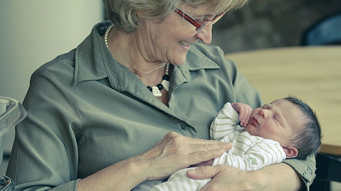 Ältere Frau mit Säugling auf dem Arm.