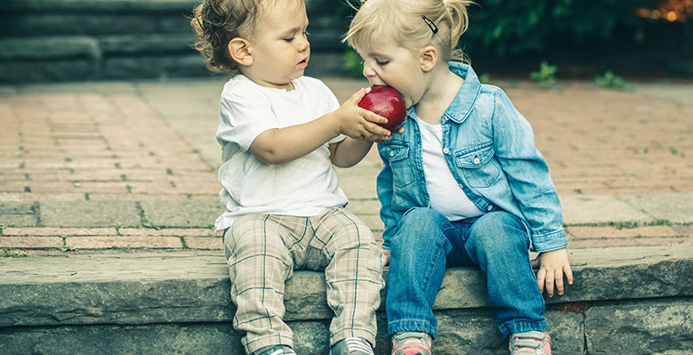  Bild: Kind isst aus der Hand eines anderen Kindes einen Apfel