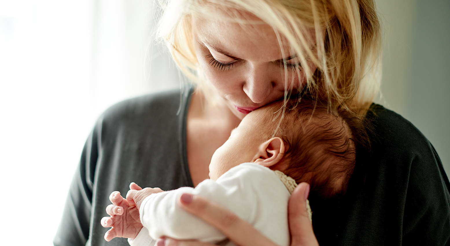 Frau küsst Baby auf die Stirn